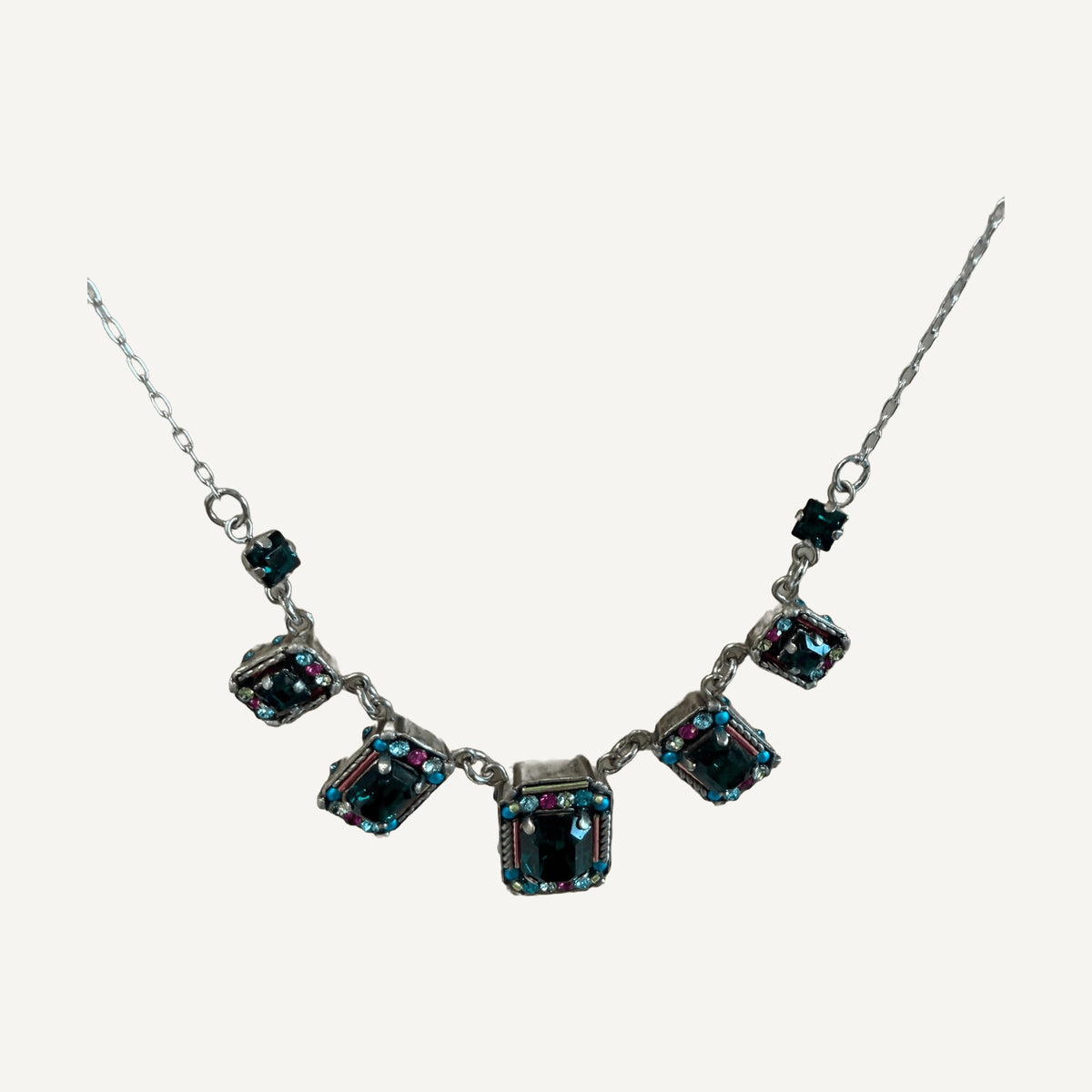 Close-up of emerald crystal settings edged with turquoise and pink crystals