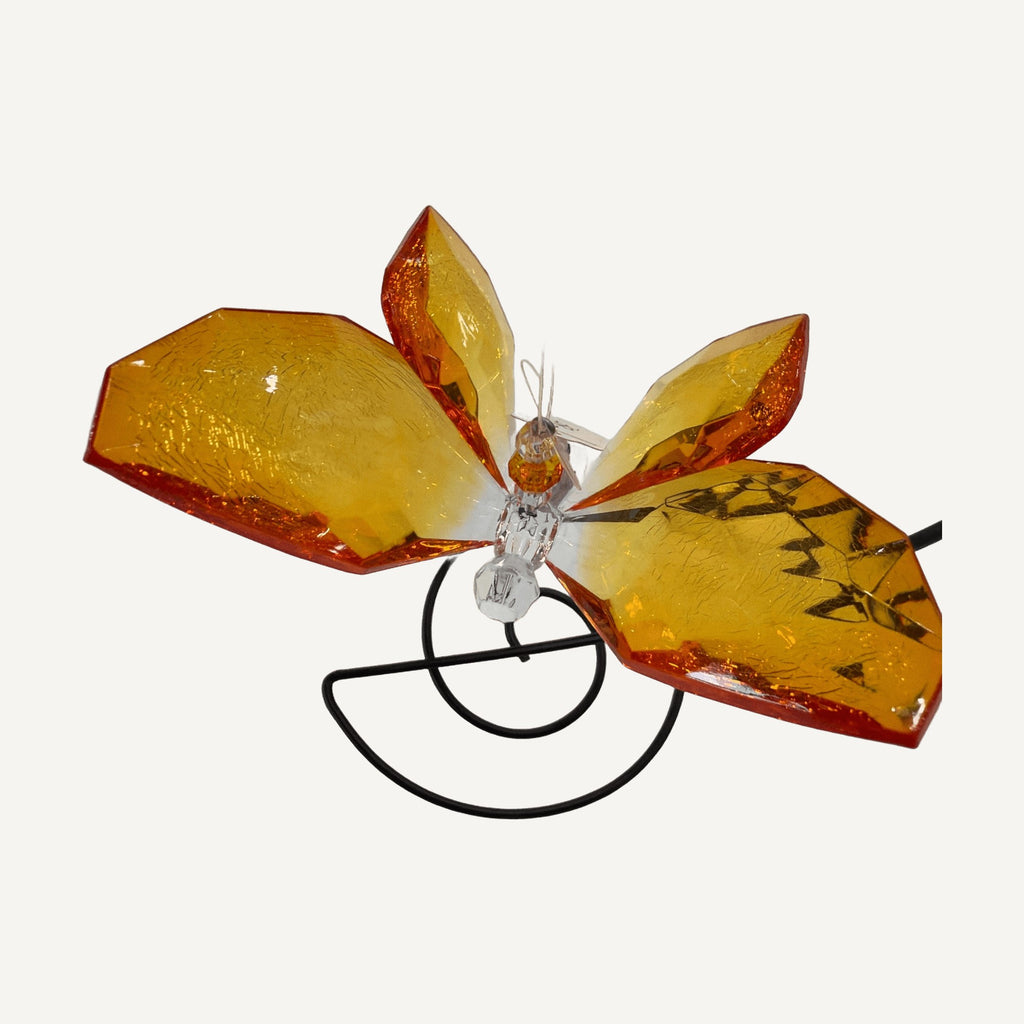 Orange faceted butterfly seen from above over a black spiral stand
