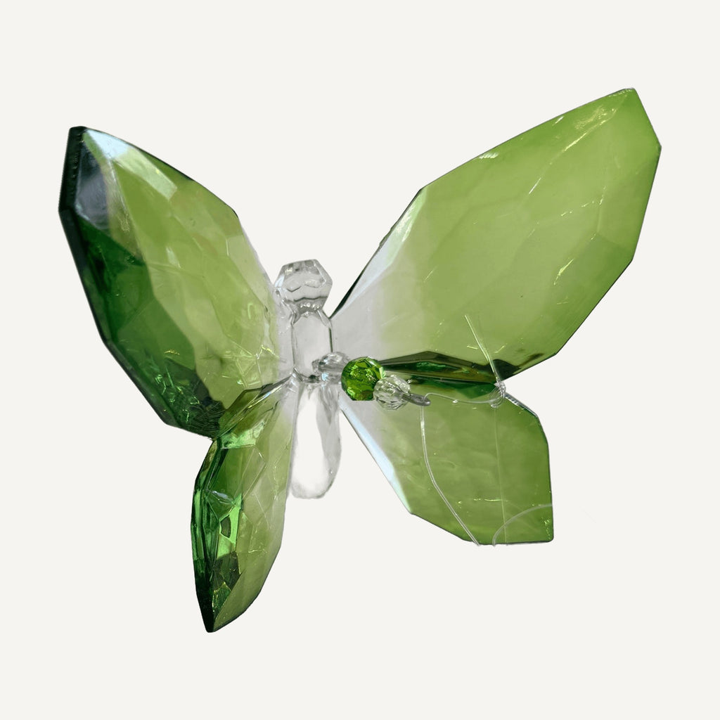 Green faceted crystal butterfly resting on a white table