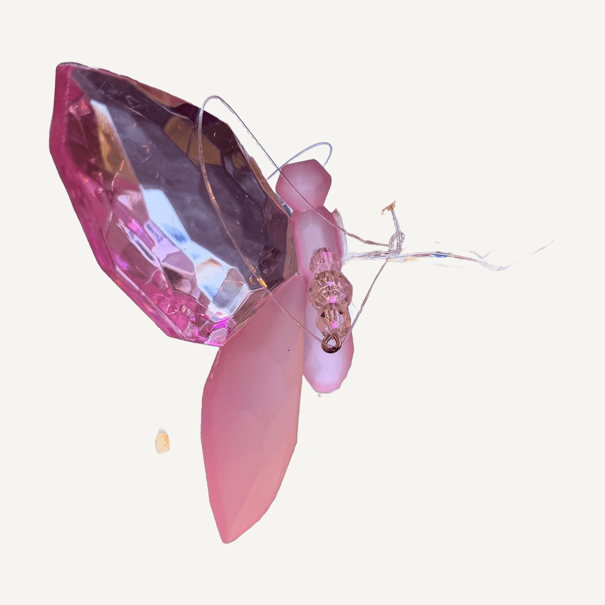 Pink and frosted faceted crystal butterfly hanging in a display case