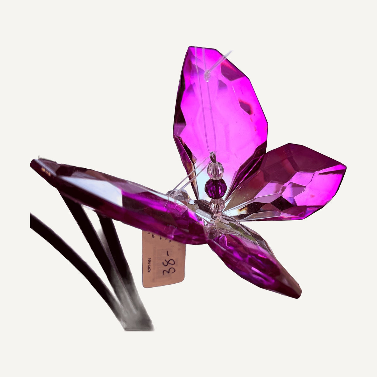 Purple faceted crystal butterfly hanging from a black stand