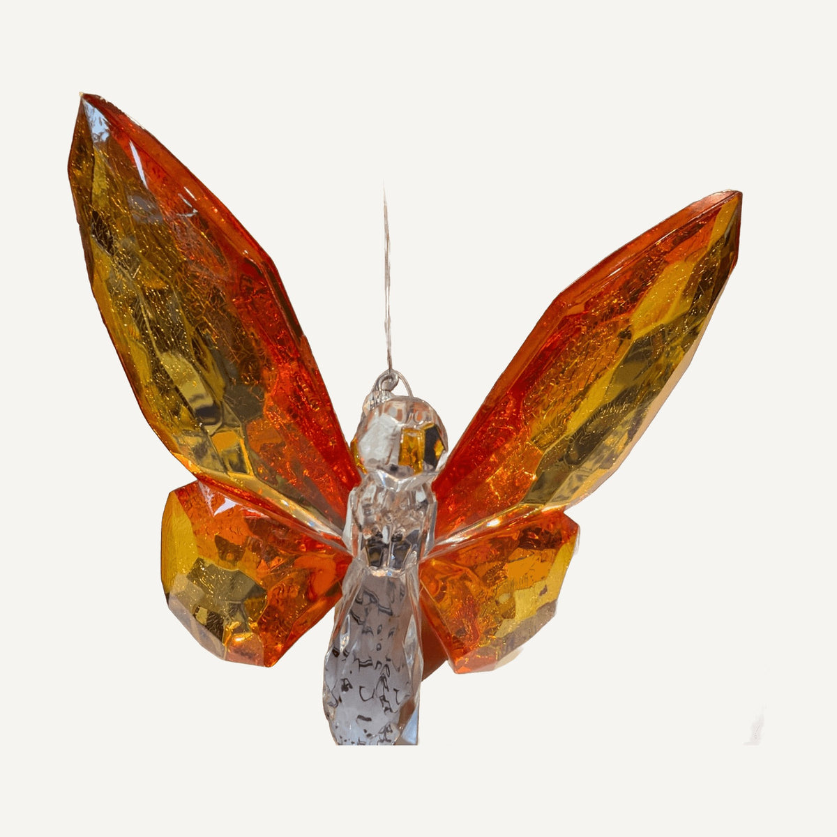 Orange and amber faceted crystal butterfly hanging from a black stand