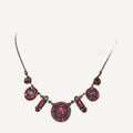 Necklace with round fuchsia crystal medallions and pink baguette links on a beige bust
