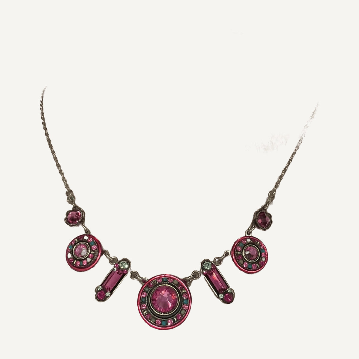 Necklace with round fuchsia crystal medallions and pink baguette links on a beige bust