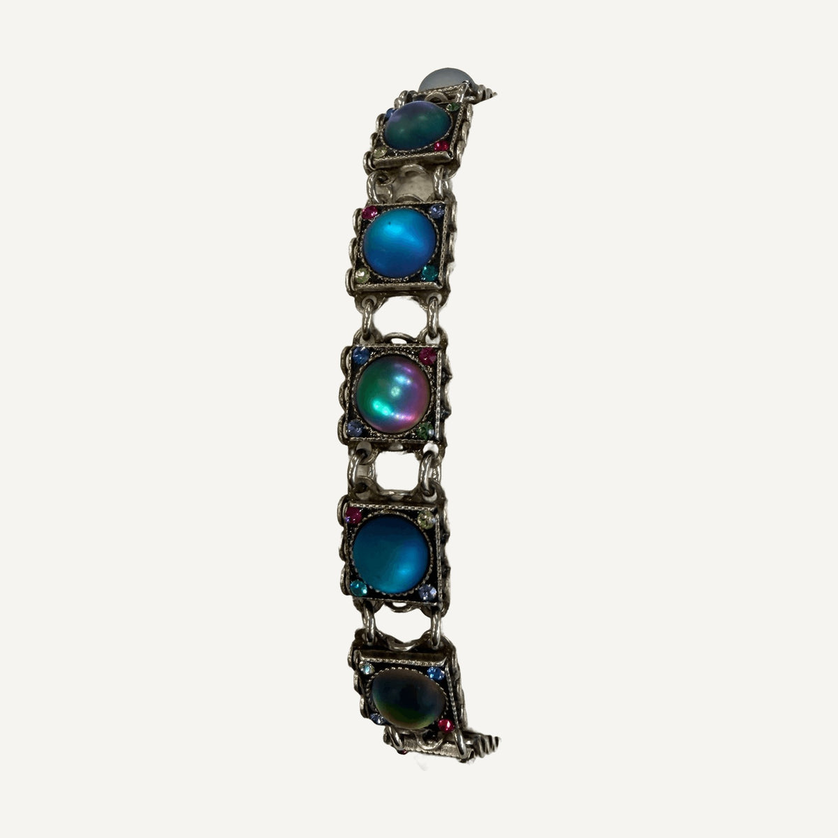 Close-up of blue and iridescent cabochon links on a cream bracelet pillow