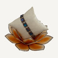 Blue cabochon link bracelet on a cream pillow on an orange glass lotus