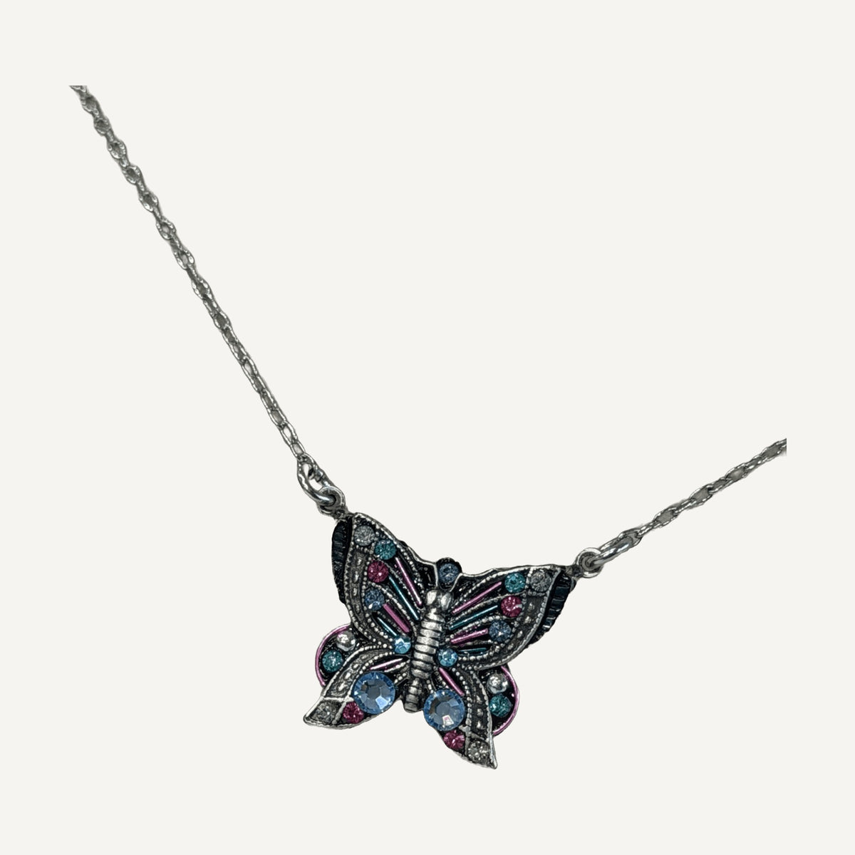 Close-up of butterfly pendant with periwinkle and pink crystals