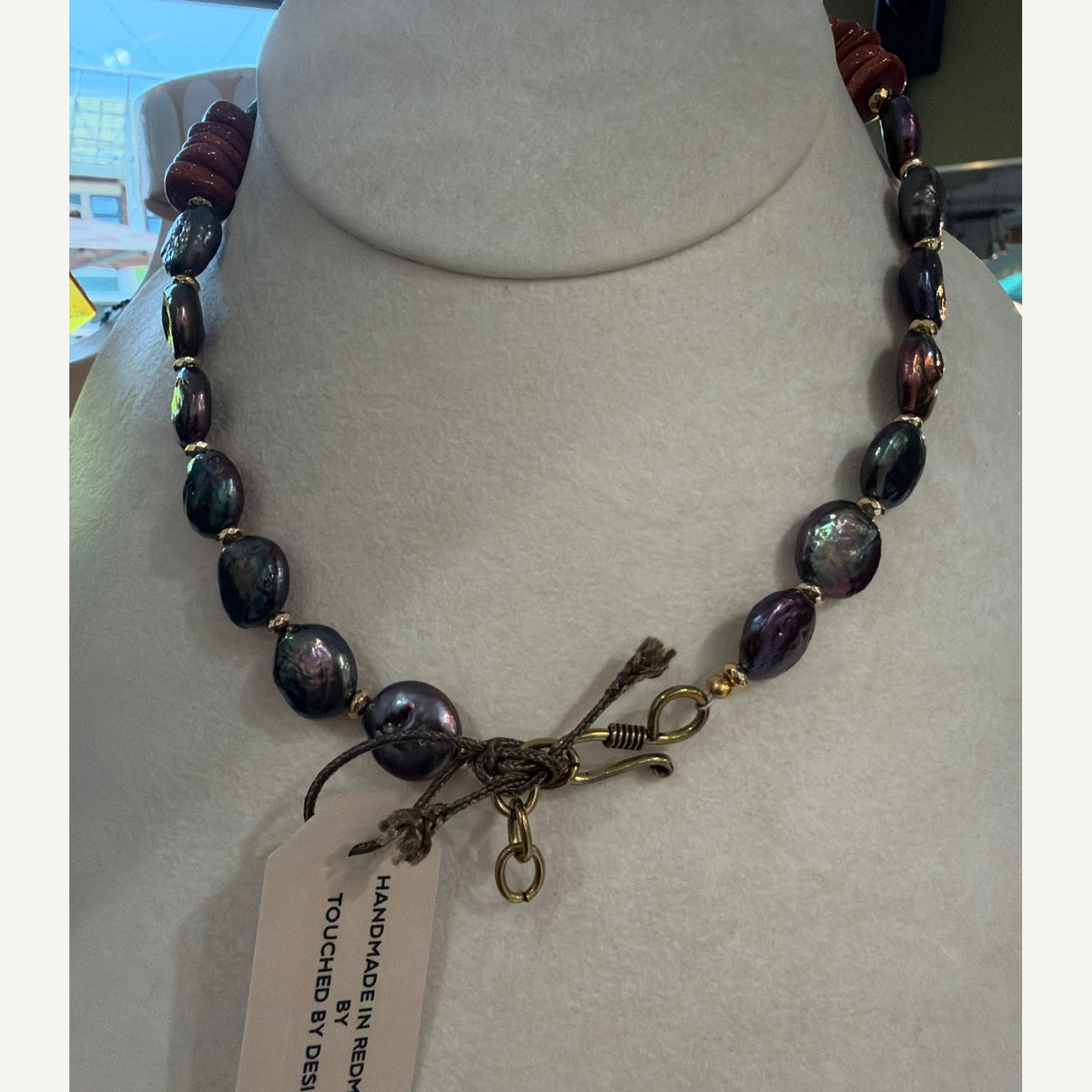 Back of the pearl necklace showing the gold-tone hook clasp and Touched By Designs handmade tag