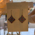 Diamond-shaped mosaic drop earrings with red crystals and turquoise accents on a Firefly card